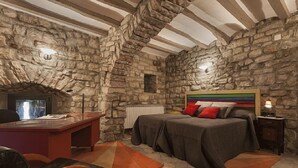 Een slaapkamer met stenen muren, een bed, een bureau en een stoel.
