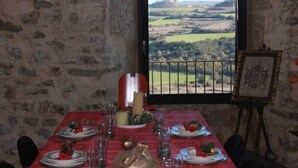 Een eettafel gedekt met borden, glazen en een kaars, met uitzicht op een prachtig landschap.