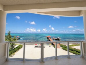 A balcony with a view of a beach and the ocean. - BEACHFRONT! 2BR/2.5BA at Grand Caribe Belize! Large, private OCEANFRONT Balcony! (San Pedro)