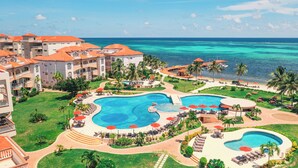 Un resort con diverse piscine, una spiaggia e vista sull'oceano.