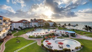 Un resort con diverse piscine, aree salotto all'aperto e vista sull'oceano.