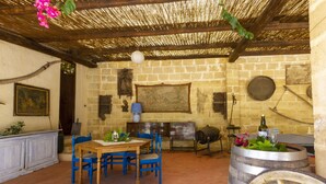 Un comedor rústico con una mesa de madera y sillas azules, rodeado de paredes de piedra y un techo de paja.