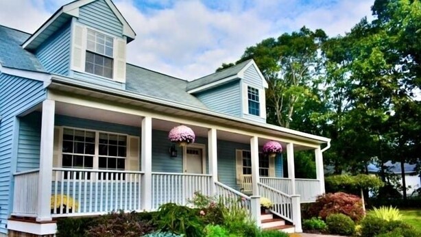 A two-story house with a porch, a front door, and a small staircase leading to the entrance.