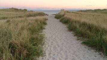 Stroll along the beach, flanked by lush greenery, to the sign marking the beach's entrance.