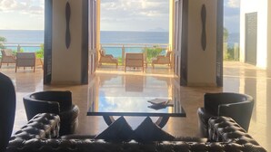 A spacious room with a large glass table and leather chairs, leading to a balcony with a view of the sea. - The Cliffs 2BR 2.5BA Apt Private Beach Sleeps 5
Luxury Oceanfront Apartment (Cupecoy)