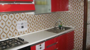 A kitchen with red cabinets, a white countertop, and a patterned backsplash. - Villa Bosa, Waterfront apartment in Bosa area, 10 meters from beach WI (trasnuraghes)