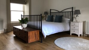 A bedroom with a bed, bedside tables, a dresser, a radiator, and a window.