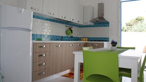 A modern kitchen with white cabinets, a stainless steel range hood, and a blue-tiled backsplash. - Saturday-Saturday-L'ondazzurra stays: a vacation without contingencies!  (Marina di Mancaversa)