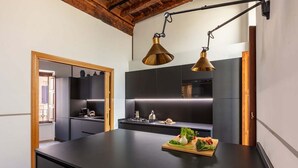A modern kitchen with a central island, black cabinetry, and a hanging brass pendant light. - Experience Collection by ROMAC Margana Palace w/ terrace & wellness (Roma)