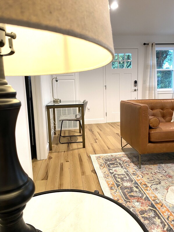 A living room with a brown leather sofa, a patterned rug, and a table with a chair.