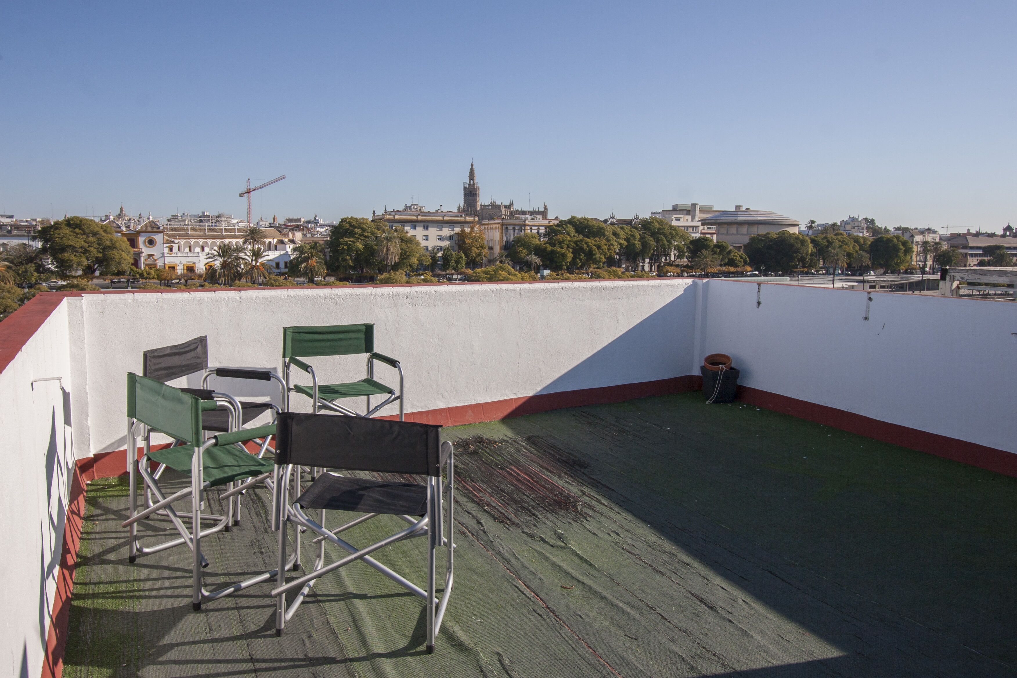 A rooftop terrace with a view of a cityscape, including a prominent building with a clock tower.