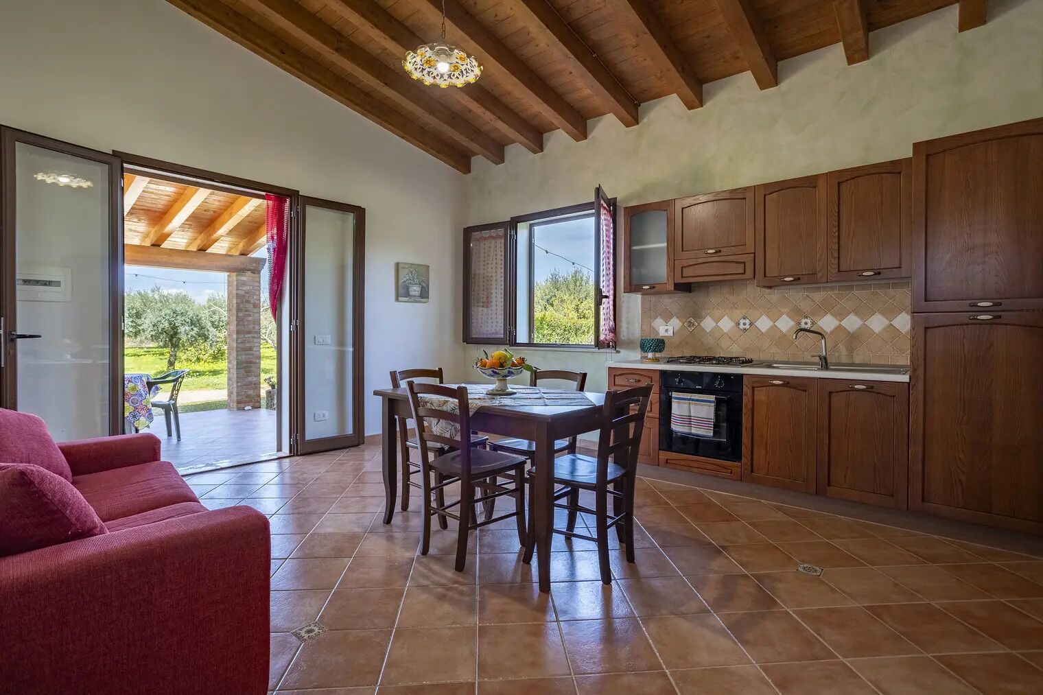 A kitchen with wooden cabinets, a dining table with chairs, and a sliding glass door leading to an outdoor area.