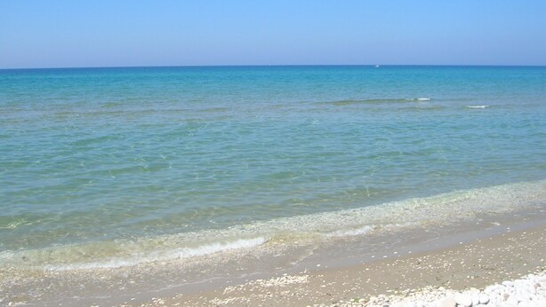 A beach with clear water and a sandy shore.