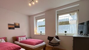 Une chambre avec deux lits en bois, un bureau, une chaise et un téléviseur.