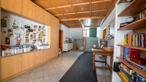 Une pièce spacieuse avec un plafond en bois, une longue moquette noire, une table en bois sur laquelle se trouve un panier, ainsi que des étagères remplies de livres et d’objets décoratifs.