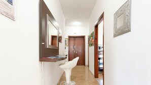A hallway with a white bar stool, a mirror, and a wooden door at the end. - Di Palma 4 Family House - Lecce Selection (Lecce)