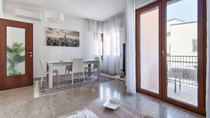 A modern living room with a dining area, a large sliding glass door to the outside, and a cityscape painting on the wall. - Di Palma 4 Family House - Lecce Selection (Lecce)
