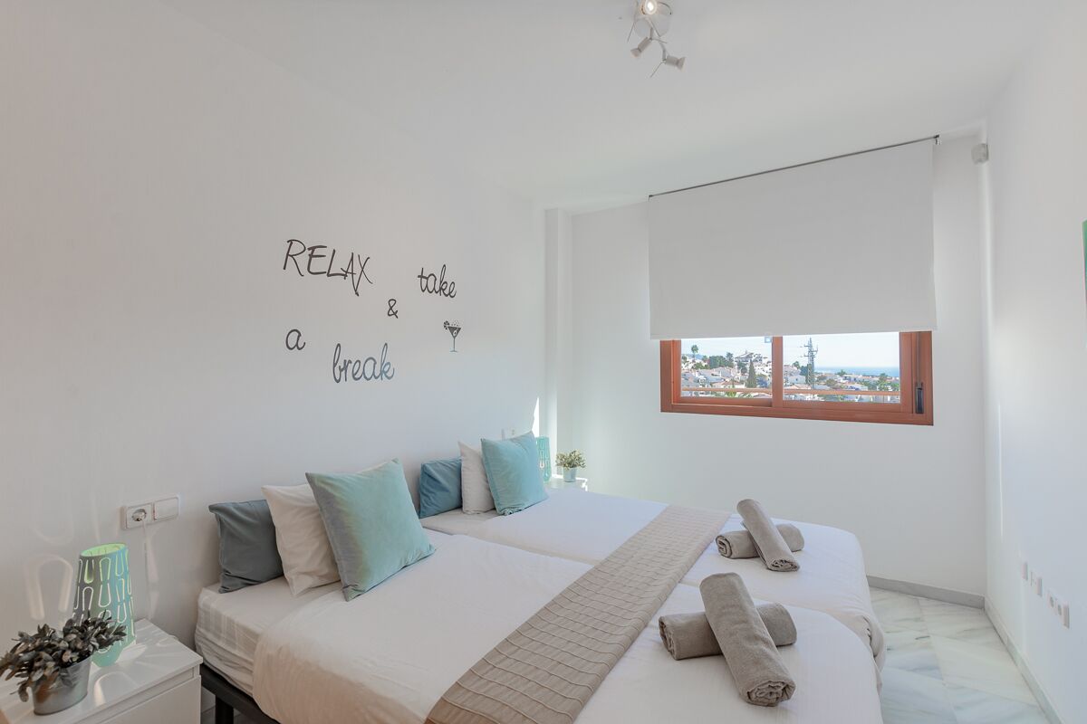 A hotel room with two beds, a view of the city, and a wall with motivational writing.