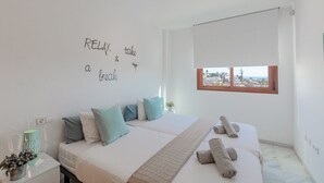 Ein Hotelzimmer mit zwei Betten und Blick auf die Stadt, an der Wand motivierende Schriftzüge.