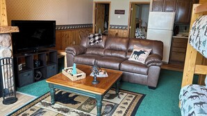 A cozy living room with a brown leather sofa, a wooden coffee table, and a television.