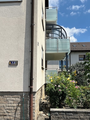 Enjoy a comfortable living space with a balcony offering views of the surrounding area, a well-maintained garden, and a stone wall.