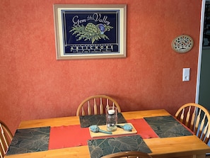 Enjoy meals in this dining area with a wooden table for four, adorned with a decorative centerpiece and a framed sign.