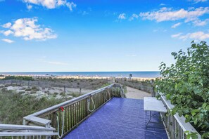 A wooden deck with a metal railing overlooking a beach.