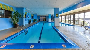 Une piscine intérieure avec des lignes de nage clairement délimitées, des panneaux de sécurité et des plantes en pot.