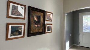 Un couloir avec des œuvres d’art encadrées accrochées au mur et une porte dotée d’une fenêtre.