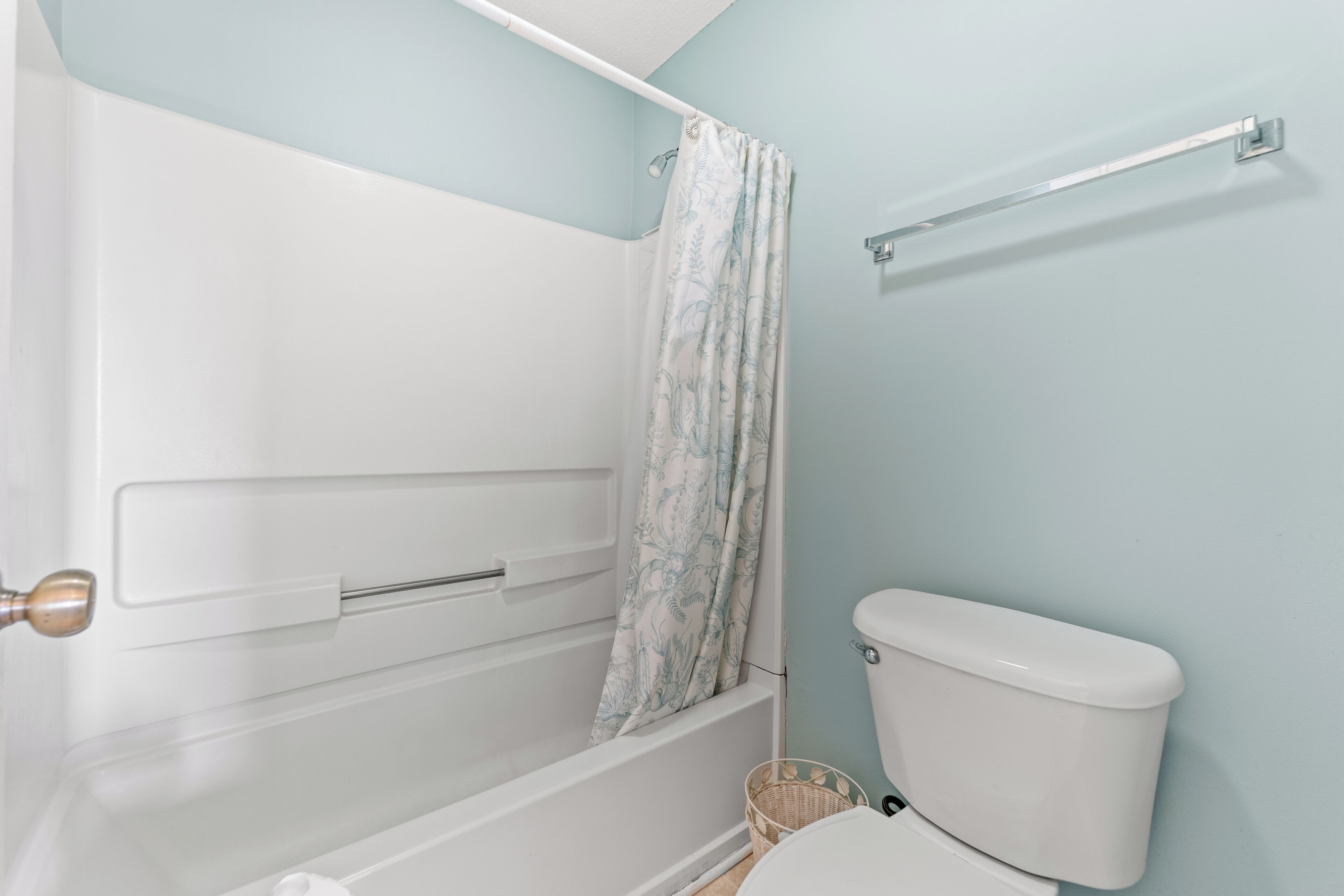 A bathroom with a shower, toilet, and a basket.