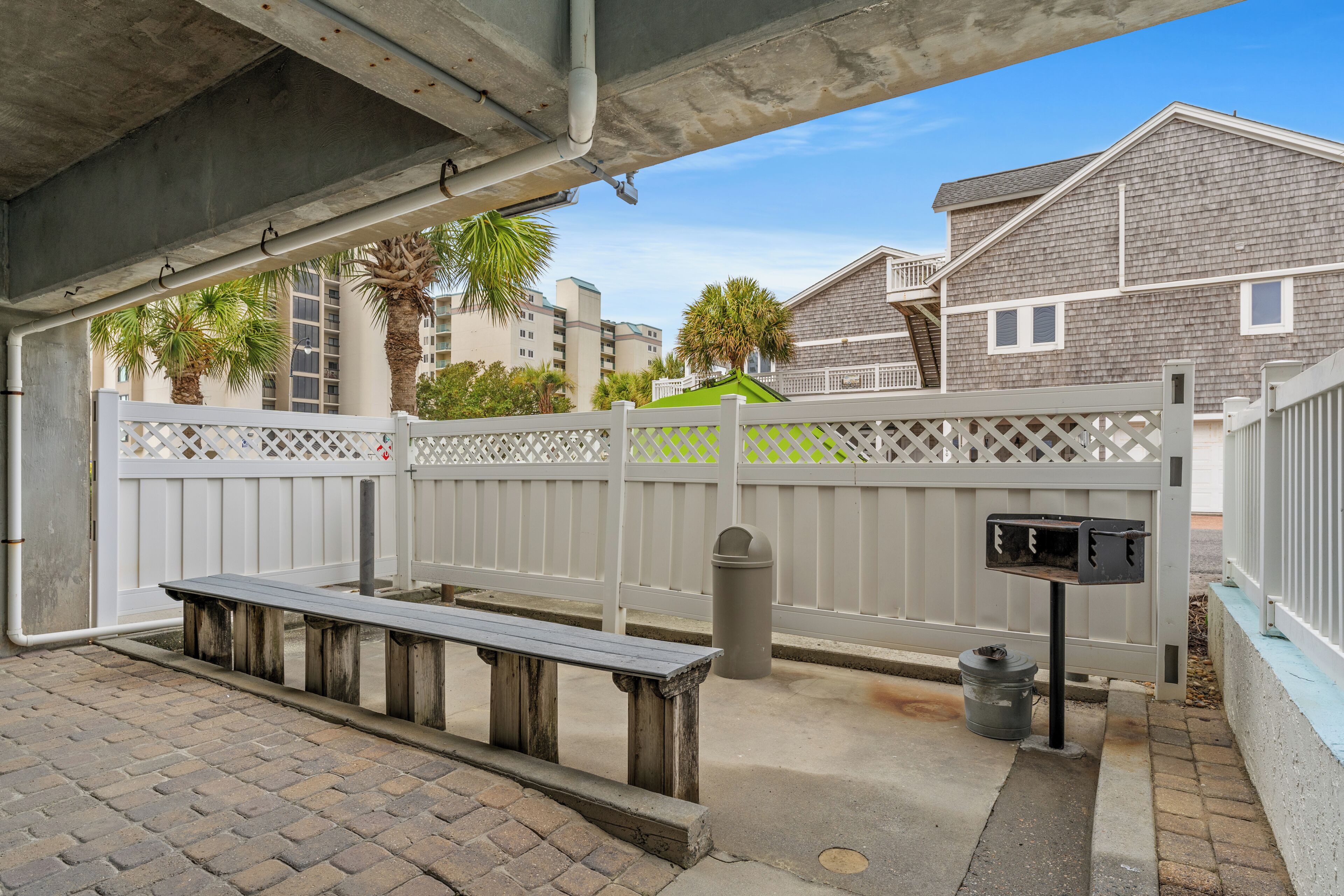 A covered outdoor area with a wooden bench, a trash can, and a mailbox.