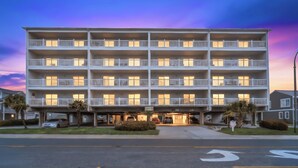 A multi-story hotel with balconies, a parking area, and a street view. - Spacious 2 Bedroom/2 bathroom Condo with Ocean View, Pool, Elevator, and Balcony (North Myrtle Beach)