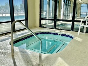 A small indoor pool with a metal ladder, tiled edges, and a view of the beach through large windows. - Beautiful 2nd Floor Condo located on the Beach with Views of The Pass (Orange Beach)