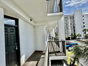 A modern building with a white exterior, a black door with the number 203, and a balcony with a metal railing. - Beautiful 2nd Floor Condo located on the Beach with Views of The Pass (Orange Beach)