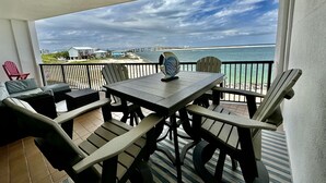 Un balcone con tavolo e sedie, vista sulla spiaggia e sull'oceano.