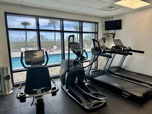 A gym with treadmills, an elliptical, and a stationary bike, overlooking a pool area. - Beautiful 2nd Floor Condo located on the Beach with Views of The Pass (Orange Beach)
