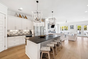 A spacious kitchen with white cabinetry, a central island with stools, and pendant lighting.