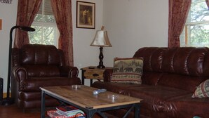 A living room with leather sofas, a wooden coffee table, and a lamp. - CEDAR CREST CABIN NEAR DOUGLAS LAKE. 30 MILES AWAY FROM GATLIN BURG.   (NEWPORT)