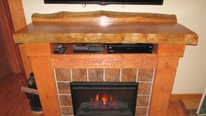 A fireplace with a wooden mantel displaying a television, remote controls, and a DVD player. - CEDAR CREST CABIN NEAR DOUGLAS LAKE. 30 MILES AWAY FROM GATLIN BURG.   (NEWPORT)