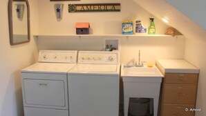 A laundry area with two washers and a dryer, a sink, and a shelf with cleaning supplies. - Private Retreat in the Rocky Mountain Front with a Million Dollar View  (Choteau)
