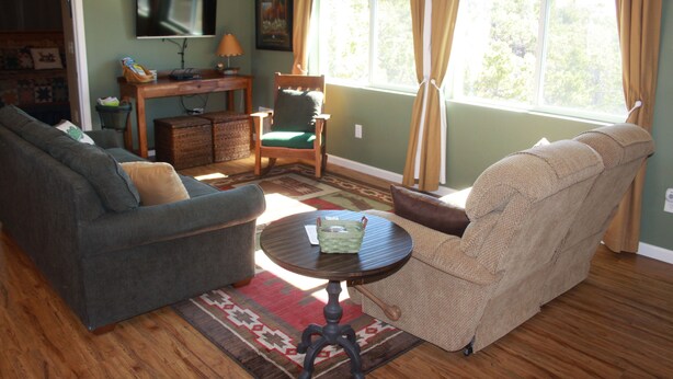A living room with a sofa, armchair, and a small table with a basket. - Private Retreat in the Rocky Mountain Front with a Million Dollar View  (Choteau)
