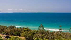 A coastal view with clear blue sea, distant land, and dense greenery. - Ocean View 1 - Rainbow Beach. Luxury With Unrivalled Views. Stunning views. (RAINBOW BEACH)