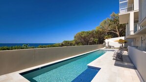 A rooftop pool with a clear view of the ocean, surrounded by greenery and a modern building. - Ocean View 1 - Rainbow Beach. Luxury With Unrivalled Views. Stunning views. (RAINBOW BEACH)
