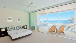 A bedroom with a bed, a ceiling fan, and a balcony with chairs. - Ocean View 1 - Rainbow Beach. Luxury With Unrivalled Views. Stunning views. (RAINBOW BEACH)