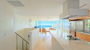 A modern kitchen with a large island, a dining area with a view of the ocean, and a spacious living area with a balcony. - Ocean View 1 - Rainbow Beach. Luxury With Unrivalled Views. Stunning views. (RAINBOW BEACH)