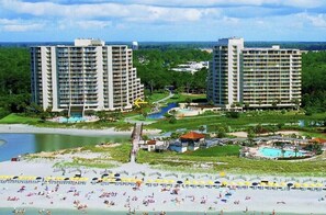 Un resort con due edifici moderni, una spiaggia e una zona piscina.