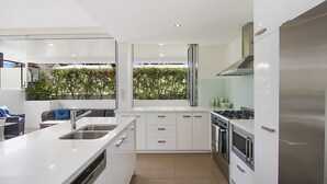 A modern kitchen with a large island, stainless steel appliances, and a view of greenery outside. - Rainbow Bay Villa - Spacious and Luxurious (Coolangatta)