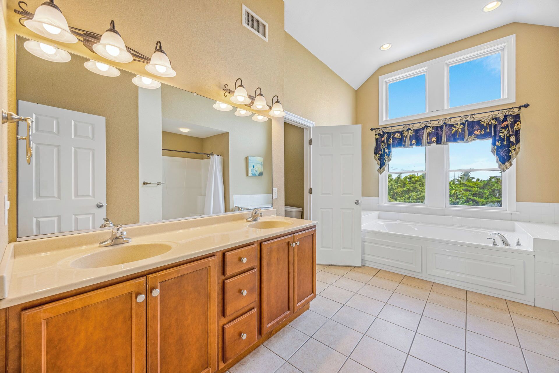 A bathroom with a double sink vanity, a large mirror, and a shower area.