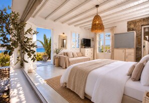 Quarto com cama grande, televisão e vista para o mar.