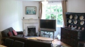 Una sala de estar con sofá, televisión, chimenea y mesa de comedor.